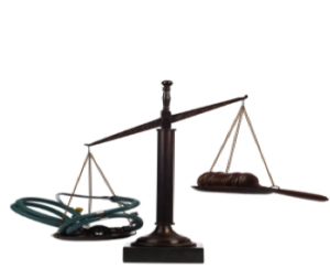 A classic scale, as in the scales often held by Lady Justice, shows two sides. The heavier has a healthcare provider’s stethoscope resting upon it. 