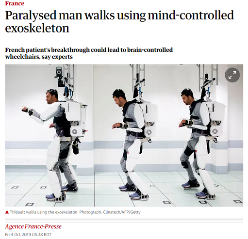 A screenshot from a Guardian article shows the headline "Paralysed man walks using mind-controlled exoskeleton: French patient's breakthrough could lead to brain-controlled wheelchairs, say experts." The date is Friday Oct 4 2019.  The byline is Agence France-Presse. There are three images showing a man strapped into a bulky white exoskeleton that holds his legs, his torso, and his arms in place.  Each part of his body is only enclosed on one side (the back of his arms, the back of his legs, his back). The device appears to be attached loosely to the ceiling on a track, presumably to prevent falling. Each of three shots shows the man at a different point in the room, in a different walking body position.